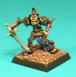 Pose 1, variant A. This Githyanki warrior carries a curved scimitar in his right hand. He wears an ornate combination of chainmail and scalemail, with strips of leather bound around his feet, lower legs and wrists. He wears a narrow, flowing skirt and a delicately jewelled gorget. This particular variant wears a jewelled headband, and sports the typical Githyanki hairstyle; swept back and upwards into a forwards-pointing peak. He is looking straight forwards with his mouth slightly open in a snarl.